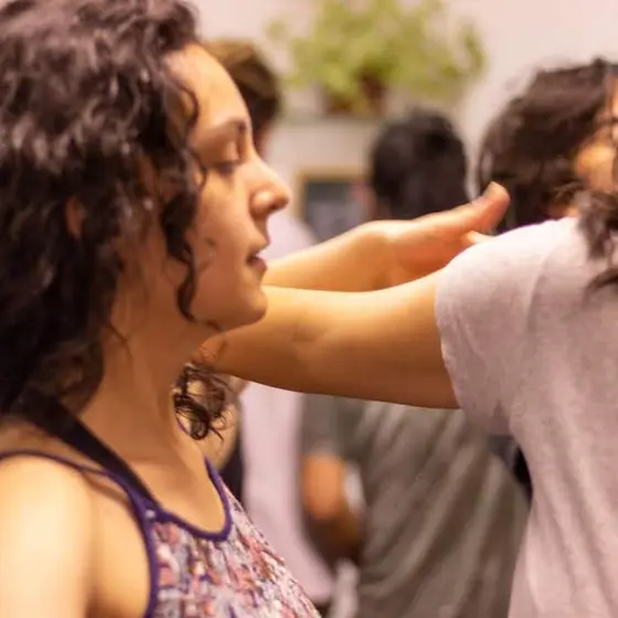 Duas alunas dançando bem perto, de braços dados, uma delas de olhos fechados