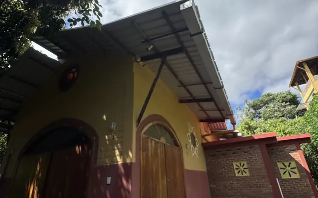 Chalé amarelo com portas de madeira em arco
