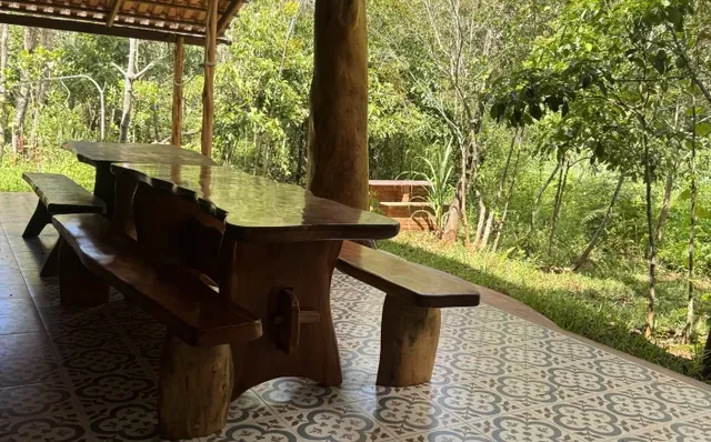 Mesa rústica de madeira numa varanda cercada de verde